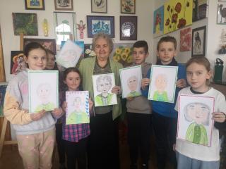 Dzieci oraz Pani Irenka z portretami kobiety.