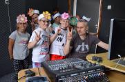 W studiu nagrań Krzysztof Roszko z dziećmi. Dzieci mają na głowach opaski z kwiatami.