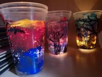 Kolorowe lampiony zrobione z plastikowych kubeczków. Na lampionach namalowane drzewa, nietoperze, ptaki.