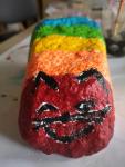 Kolorowy kot namalowany na kamieniu.