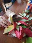 Dziecko w trakcie przyklejania liści do papierowego koła.