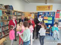Kobiety z Klubu seniora w Orzyszu rozdają dzieciom ksiązki "Pogwarki dziadka Otto". W sali bibliotecznej. 