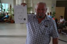 Mężczyzna uśmiecha się, trzyma w ręku kartkę ze swoim portretem, w rogu kartki logo z tygrysem.