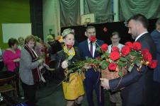 Burmistrz oraz Radni Orzysza trzymają róże. Mężczyzna z prawej trzyma kosz z różmi. W tle kobiety 