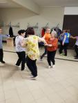 Kobiety z Uniwersytetu Trzeciego Wieku tańczą w grupach. Zajęcia "Ruch to zdrowie" z okazji Pierwszego Dnia Wiosny 