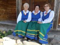 Trzy kobiety z zespołu Orzyszanki w strojach ludowych.