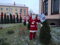 Święty Mikołaj na Polanie Kultury w Orzyszu. Za nim drzewa przystrojone w czapki.