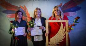 Elżbieta Mroczkowska, Grażyna Bukowska, Małgorzata Malik laureatki w kategorii KOBIETA PRZEDSIĘBIORCZA, na tle kolorowych skrzydeł.