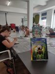 Dzieci siedzą przy stole i malują w Czytelni biblioteki