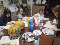 Czwórka dzieci siedząca przy stole z pędzelkami w rękach, w trakcie pracy z kolorami.
