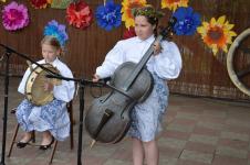 Dwie dziewczynki graja na instrumentach. Występ na scenie podczas XIII Orzyskiego Spotkania Folklorytycznego.