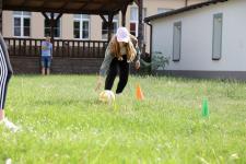 Dziewczynka tocząca piłkę po trawie.