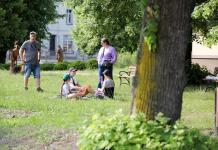 Grupka osób. Kobieta i dwojka dzieci siedzą na kocu na trawie, obok stoi kobieta, za nimi idzie mężczyzna. Na Polanie Kultury w Orzyszu.