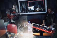 W studiu nagrań Pani Dyrektor Polany Kultury gra na gitarze, obok niej mężczyzna grający na keyboardzie,