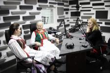 Dwie kobiety w studiu Polskiego Radia Orzysz, przed nim Joanna Kamieniecka- Dyrektor Polany Kultury w Orzyszu. Przed nim na stole statywy mikrofonowe.