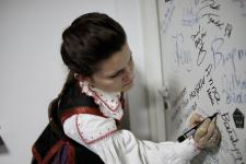 Kobieta w stroju ludowym podpisuje się na drzwiach w studiu Polskiego Radia Orzysz.