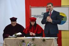 Trzy osoby przy stoliku, na stojąco przemawia Burmistrz Orzysza Zbigniew Włodkowski, po środku siedzi Pani Dziekan