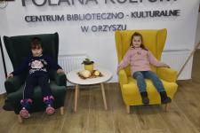 Dziewczynki siedzą w fotelach w czytelni biblioteki