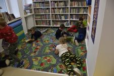 Dzieci leżą na dywanie i czytaja książeczki w kąciku dla dzieci